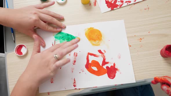 Top View of Little Boy with Mother Drawing and Painting with Hands Covered in Colorful Paint on alt