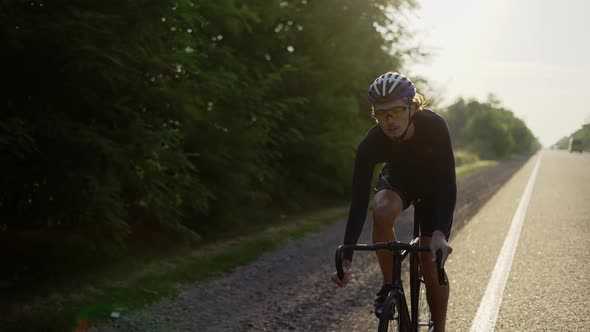Male Cyclist in Helmet Rides Bicycle Along the Track Closeup alt
