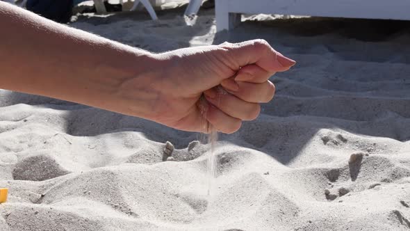 Female Hand Spills Beach Sand From Handful