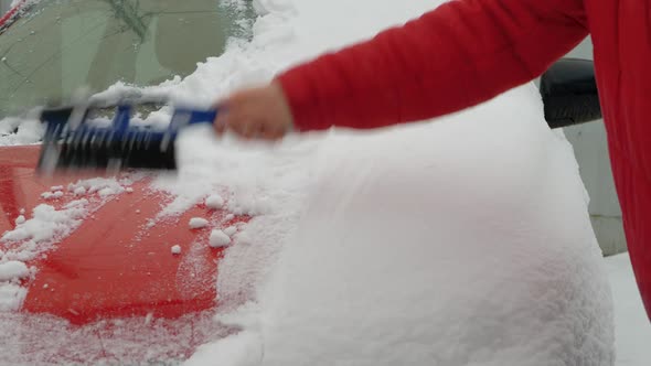 Cleans Car Hood with Brush From Snow and Rain in Winter