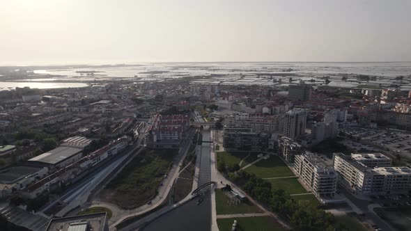 Sprawling cityscape. Ria de Aveiro urban canals towards lagoon. Aerial pullback alt