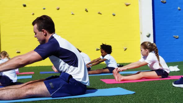 Yoga instructor instructing children in performing exercise alt