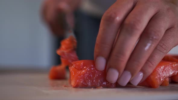 A Woman with a Knife Cuts a Red Fish Trout Into Small Pieces on a Poker Board