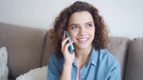 Multiethnic Young Woman Talking with Friends on Mobile Phone Sitting at Home alt
