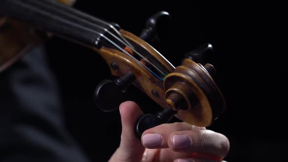 Musician Girl a Tunes Violin. Black Background. Close Up alt