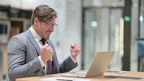 Excited Businessman Celebrating Success on Laptop in Office  alt
