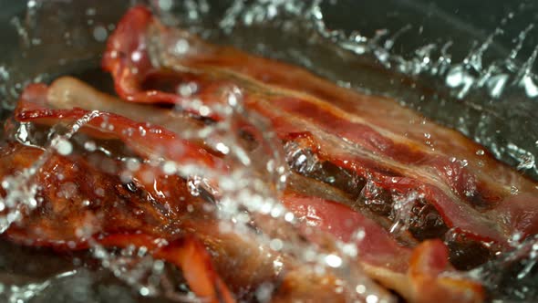 Super Slow Motion Shot of Roasted Bacon Slices Falling Into Pan at 1000 Fps alt