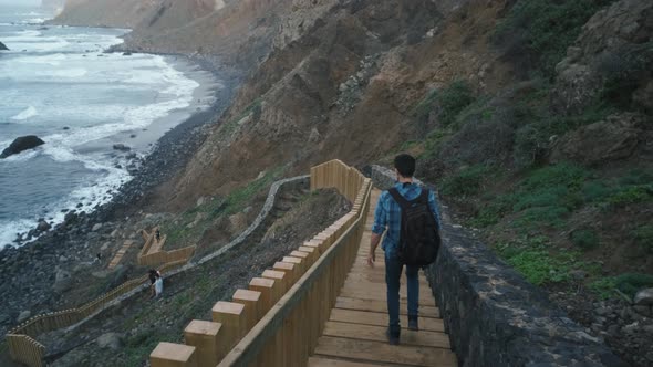Young Man Tourist Goes Down the Long Stairs to the Famous Volcanic Black Sand Beach Benijo in the alt