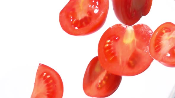 Closeup of the Fresh Tomato Halves Falling Diagonally on a White Background alt
