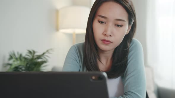 Asian woman watching lesson online looking at screen learning online courses