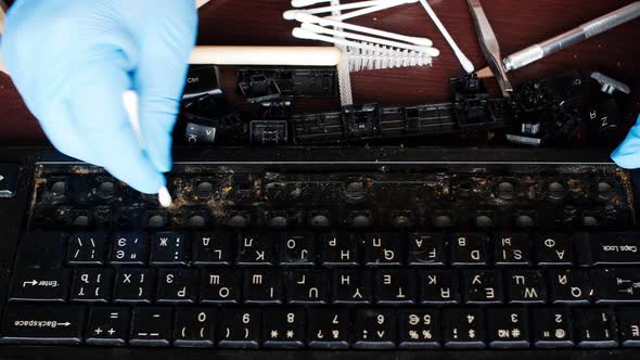 A professional computer technician uses the correct movements cleaning with a swab a keyboard