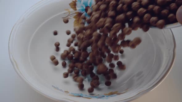 Brown Chocolate Corn Flakes Fall In A White Plate With A Pattern Of Flowers