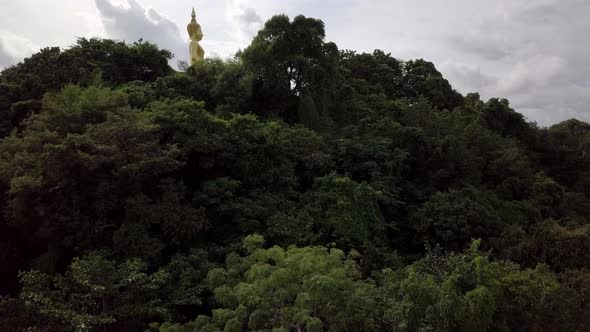 A slow aerial shot revealing a statue of Buddha, temple and fields in the distance alt