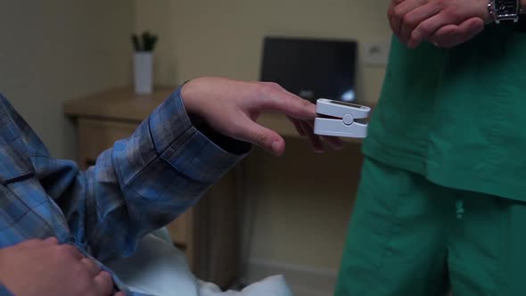 PulsDoctor attaches pulse ox on finger of patient lying on bed