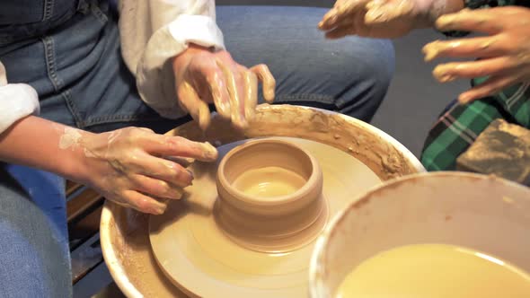 Boy and Woman Makes a Pot with Pottery Wheel in a Workshop alt