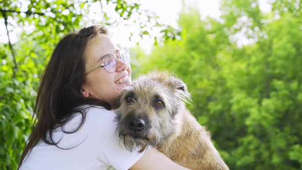 Woman in Glasses Hugging Dog in Green Park