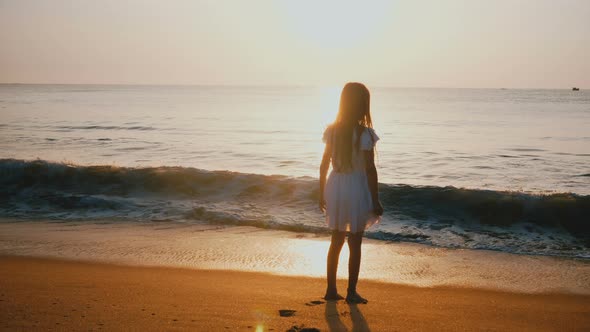 Amazing Back View Shot of Happy Excited Little Female Child Watching Ocean Wave Coming alt