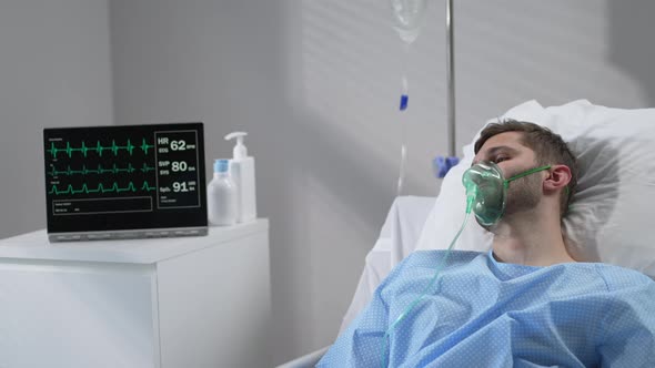 The Man Lies on the Bed in the Hospital in Oxygen Masks and Regains Consciousness alt