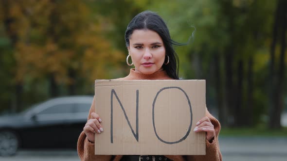Closeup Protest Girl Standing Outdoors Looking at Camera Holding Cardboard Banner NO Community alt