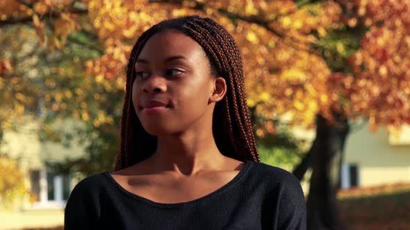 Young Beautiful Black Woman Smiles To Camera in the Park in Autumn Day alt