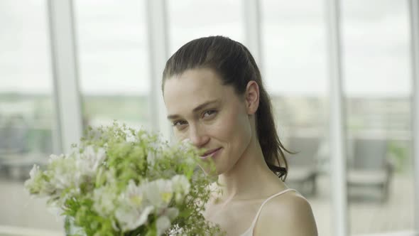 Young woman smelling bouquet of fresh flowers alt