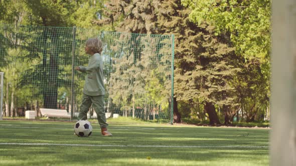 Father and Son Playing Football on Field in Park alt