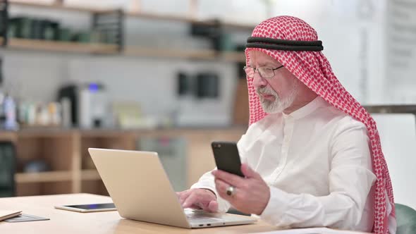 Senior Old Arab Businessman Working on Laptop and Smartphone in Caf� alt