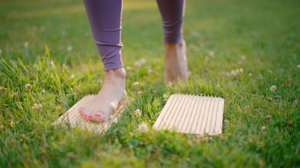 Close Up to Female Feet Step on Nail Board on Grass at Yoga Class in Park