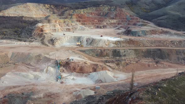 Aerial top down view of an excavator loading crushed stone into a dump truck alt