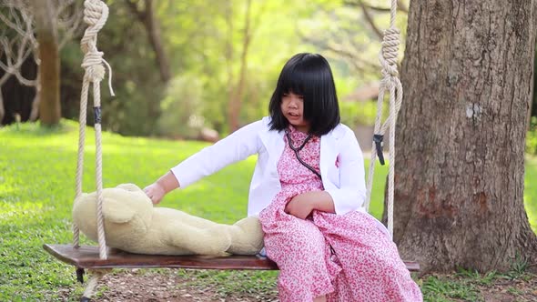 A young Asian woman playing as a teddy bear doctor.