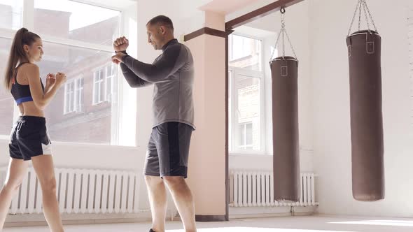 A Young Girl Conducts Kickboxing Training and Practices Hands Strikes with a Professional Boxer alt