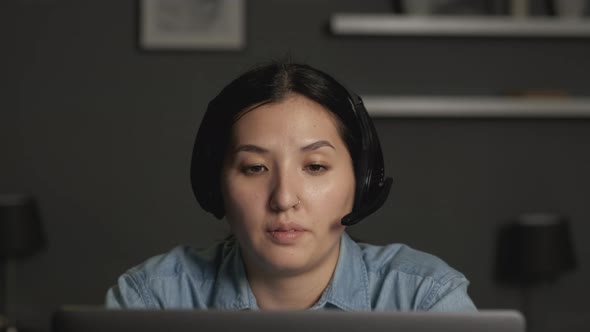 Close-Up of a Young Asian Woman Wearing Headphones with a Microphone for Work