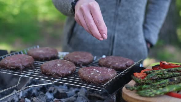 Salting Beef Burgers Cutlets Roasting on the Charcoal Barbecue Grill alt