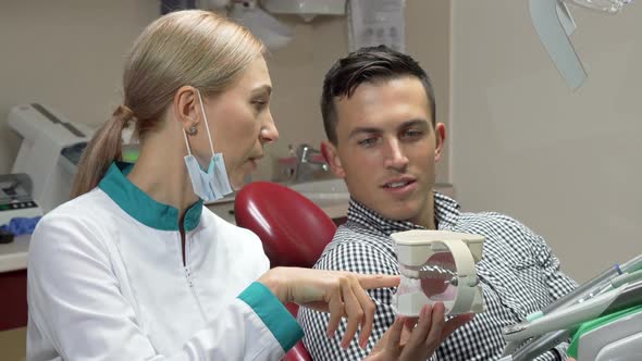 Handsome Man Showing Thumbs Up Sitting in Dental Chair, Talking To His Dentist  alt
