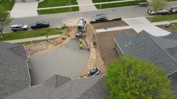 Cement crew finishing up a new residential driveway in a rural neighborhood in summer.