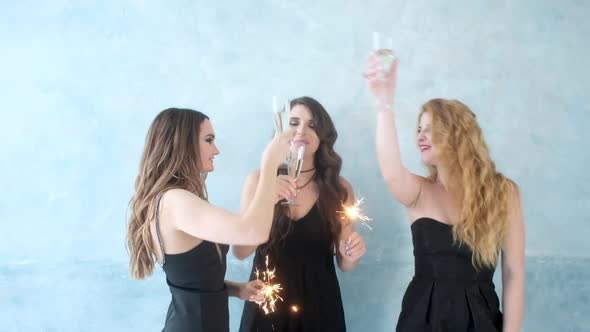 Sexy girls clink glasses with champagne. Women dance sparklers in hands alt