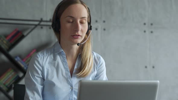 Businesswoman Sitting at Desk, Making a Call, Using Headset and Laptop alt