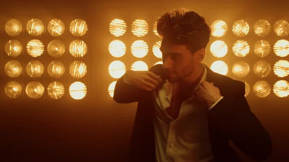 Man Model Straighten Jacket Standing in Spotlights alt