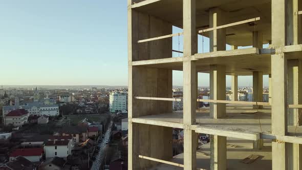 Concrete interior frame of tall apartment building under construction in a city. alt
