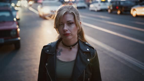 Model Hipster in Black Leather Jacket and Choker is Posing By a Road of City Street with Busy alt