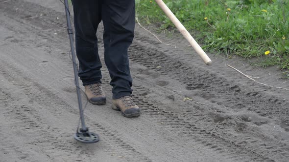 Treasure Hunter Walking on Road, Holding Metal Detector, Scanning Ground of Road