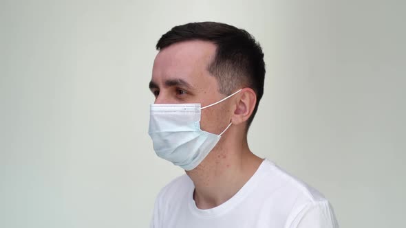 Smiling Young Happy Man Taking Off Medical Mask on White Isolated Background. alt