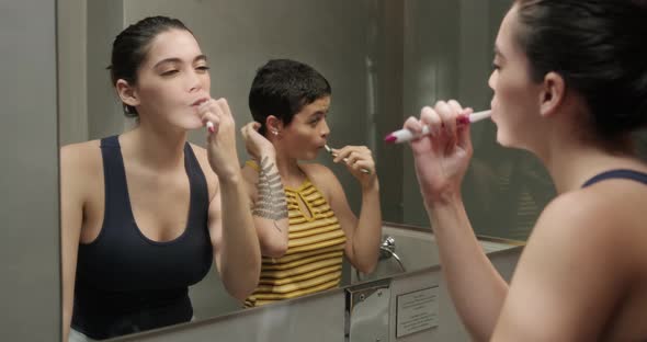 Couple of Lesbian Female Roomates in The Bathroom Brushing Teeth Together at Home