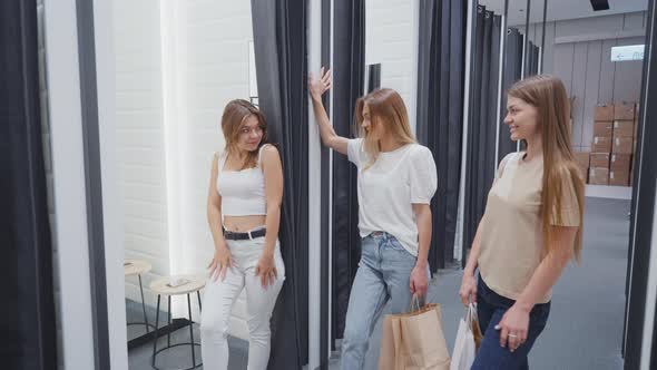 Female Trying on New Outfit and Showing It to Friends in Dressing Room alt