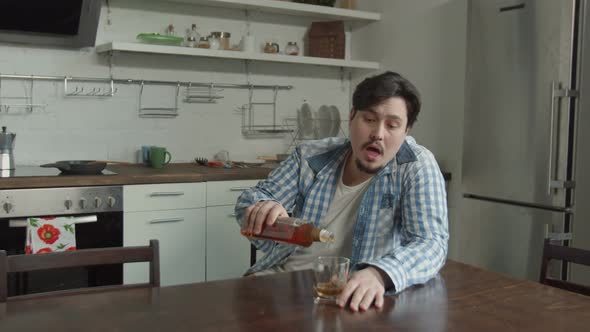 Man Drinking Alcohol Sitting at Kitchen Table alt