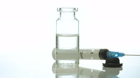 Medical Glass Bottle with Medicine Syringe Rotates Against White Background