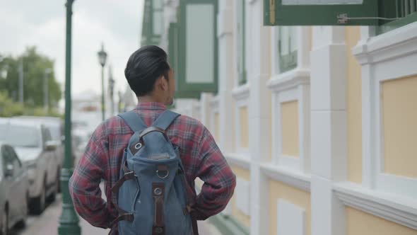 Portrait of handsome young Asian man solo tourists walking looking around on the street.