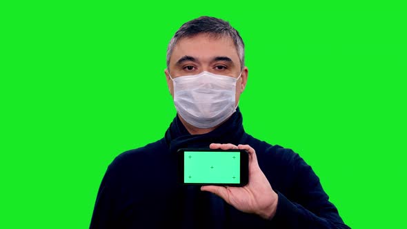 Adult Asian Man in Protective Mask Holding Smartphone with Green Screen 