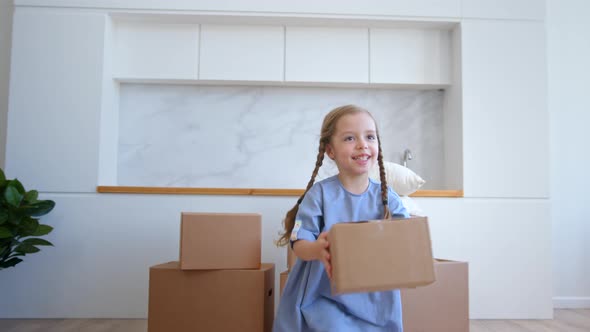 Little preschooler girl in blue dress takes brown cardboard package alt