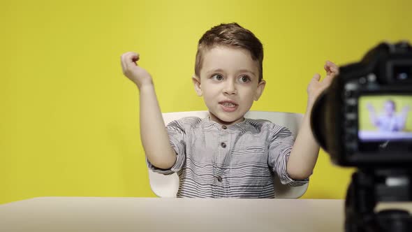 Kid blogger filming video on camera working with the laptop, at home. Online learning. Online school alt